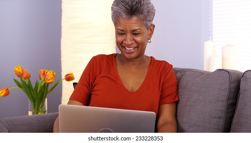 African Grandmother Laughing And Talking On Laptop