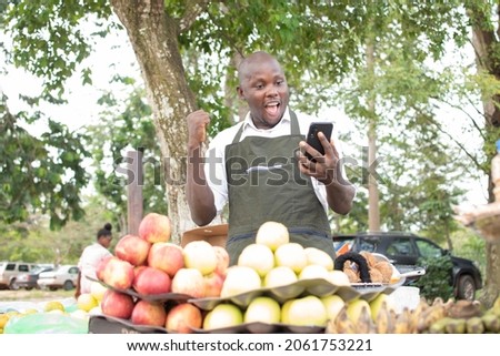 an african grocery seller using his phone