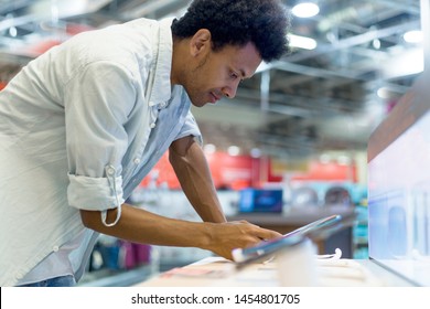 African Guy In An Electronics Store Chooses A Cell Phone To Buy