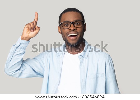 African guy raised index finger up came up with great cool fresh business idea feels happy looking at camera isolated on gray background, bright mind outstanding intellect or understanding concept