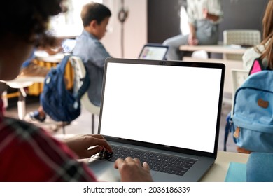 African junior school kid girl student using laptop computer with white blank empty mockup screen at desk in classroom. Online education class software website tech ads concept. Over shoulder view