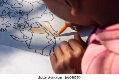 African Kid Exercising On A Coloring Book In The Classroom