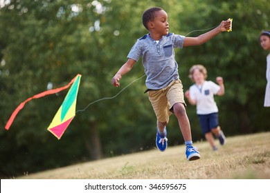 African Kid Having Fun Flying A Kite In The Nature 
