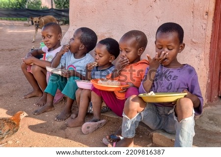african kids eating some sorghum porridge, village in botswana