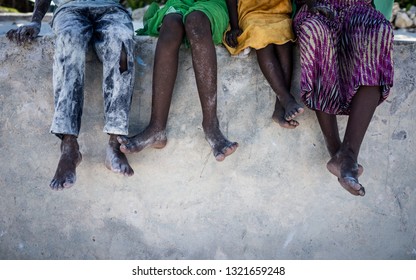 African Kids Sitting On Wall With Feet Down