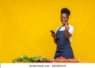 la chef africana usando su teléfono da un pulgar hacia arriba