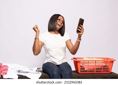 African Lady Doing Laundry Excitedly Checking Her Phone