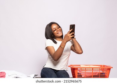 African Lady Doing Laundry Excitedly Checking Her Phone