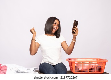 African Lady Doing Laundry Excitedly Checking Her Phone