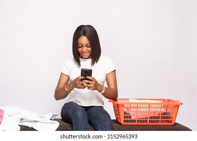 African Lady Doing Laundry Smiling While Checking Her Phone