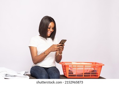 African Lady Doing Laundry Smiling While Checking Her Phone