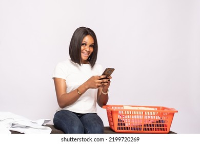 African Lady Doing Laundry Smiling While Checking Her Phone