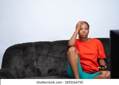 african lady feeling unhappy with what she's watching on TV