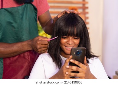 African Lady In A Hair Salon Using Her Phone