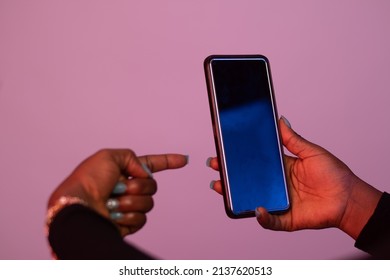 african lady holding a blank phone, points to it