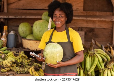 african lady holding a watermelon and money in a market