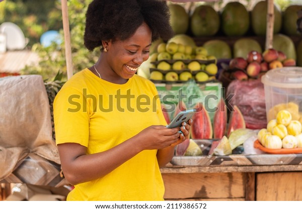 african lady using her\
phone in market