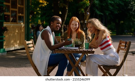 African lady very beautiful and her friends blonde hair lady and ginger hair enjoy the time together at the cafe they have a friendly conversation smiling large
