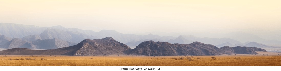 African landscape of savanna in Damaraland with mountain layers in morning haze, sunrise in Namibia. Wildlife travelling, adventures and safari tours to Africa, wide panoramic view. - Powered by Shutterstock