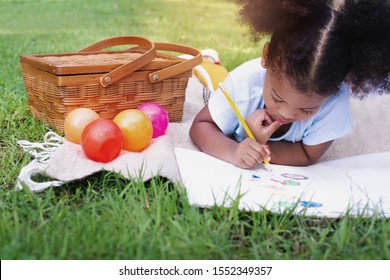 African little girl lying and drawing with colored pencils at summer park, feel happiness, outdoor education concepts - Powered by Shutterstock