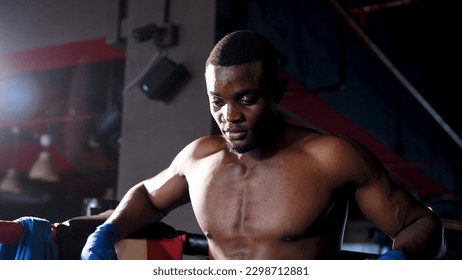 African male boxer is standing in the corner of a boxing ring preparing to meditate for the next prime fight. Boxing training requires concentration in order to beat your opponent. - Powered by Shutterstock