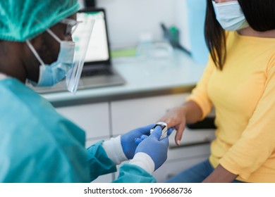 African male doctor using pulse oximeter on young woman patient finger - Measuring oxygen saturation - Coronavirus outbreak - Shutterstock ID 1906686736