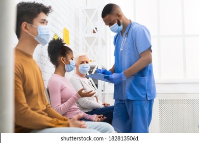 African Male Nurse Working Talking With Multiracial Patients In Hospital During Coronavirus Covid-19 Vaccination. Vaccine For Corona Virus, Covid Immunization Campaign Concept