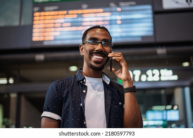 African male talking on the phone while he waits at a train station