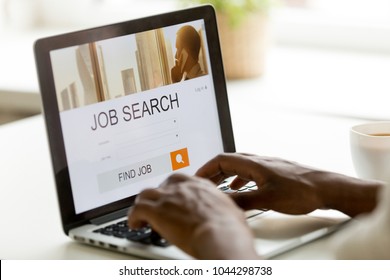 African man browsing work opportunities online using job search computer app, black jobless seeker looking for new vacancies on website page at laptop screen, recruitment concept, rear close up view
