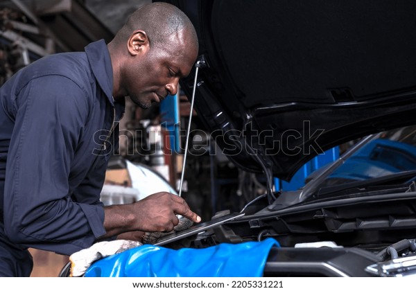 African man car mechanic using tablet checking car\
problem in auto repair service, modern African car technician\
working in automobile repair garage center, black man auto mechenic\
working with tablet