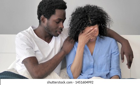 African Man Comforting Upset Wife in Bed