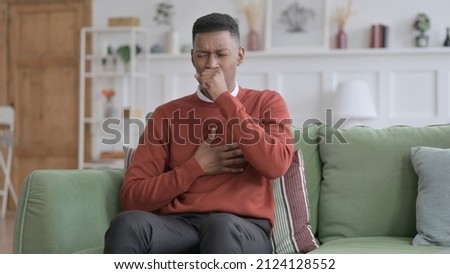 African Man Coughing while Sitting on Sofa