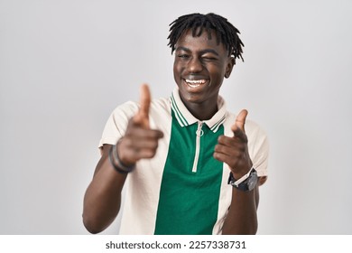 African man with dreadlocks standing over isolated background pointing fingers to camera with happy and funny face. good energy and vibes. 