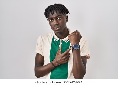 African man with dreadlocks standing over isolated background in hurry pointing to watch time, impatience, looking at the camera with relaxed expression  - Powered by Shutterstock