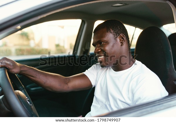 African man driving a\
car smiling side view