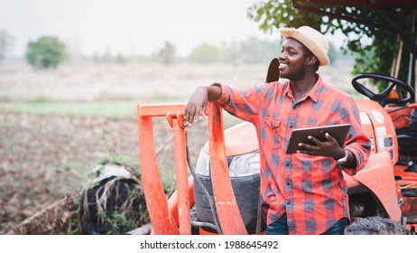 African man farmer working in the field with a tractor and using tablet - Powered by Shutterstock