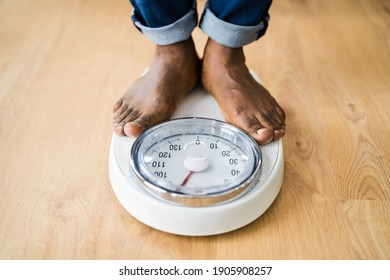 African Man Feet Standing On Weight Scale. Low Section