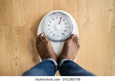 African Man Feet Standing On Weight Scale. Low Section