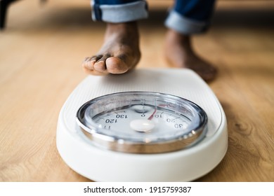 African Man Feet Standing On Weight Scale. Low Section