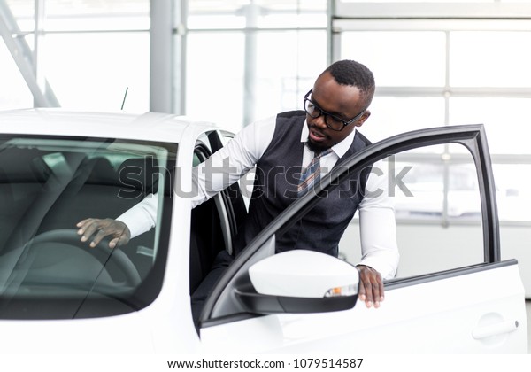 African\
man with glasses sit in the cabin of a new\
car