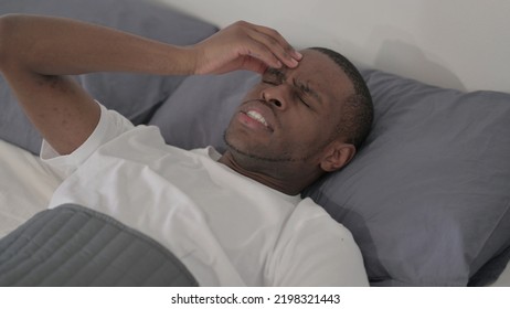 African Man Having Headache While Sleeping In Bed, Close Up