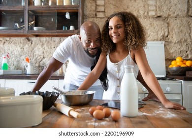 african man with his daughter in the kitchen of his house - Shutterstock ID 2200196909