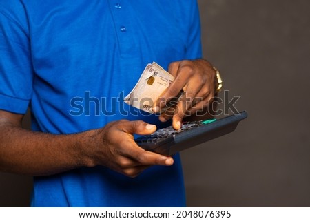 african man holding some money and using a calculator