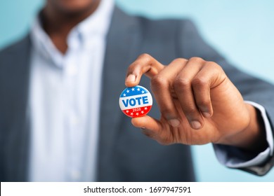 African man holding vote button on blue background for the November elections in the United States 2020, blurred - Shutterstock ID 1697947591