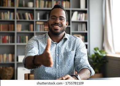 African man HR agent sit at workplace desk stretch hand for handshake greeting new applicant start job interview. Polite broker extending arm introduces himself getting acquainted with client concept - Powered by Shutterstock