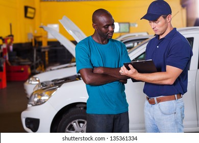 african man inside vehicle workshop with auto mechanic