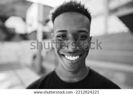 African man looking at camera inside basketball court - Main focus on nose - Black and white editing.