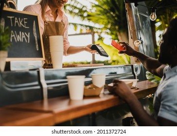 African man making contactless payment at food truck restaurant - Focus on hand holding smartphone - Powered by Shutterstock