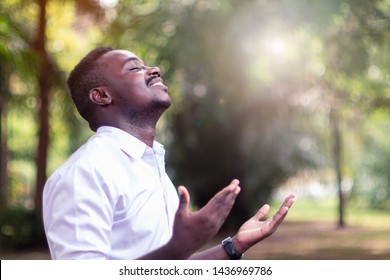 African man praying for thank god with light flare in the green nature - Shutterstock ID 1436969786