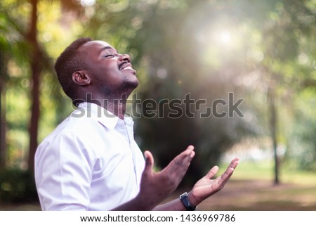 African man praying for thank god with light flare in the green nature